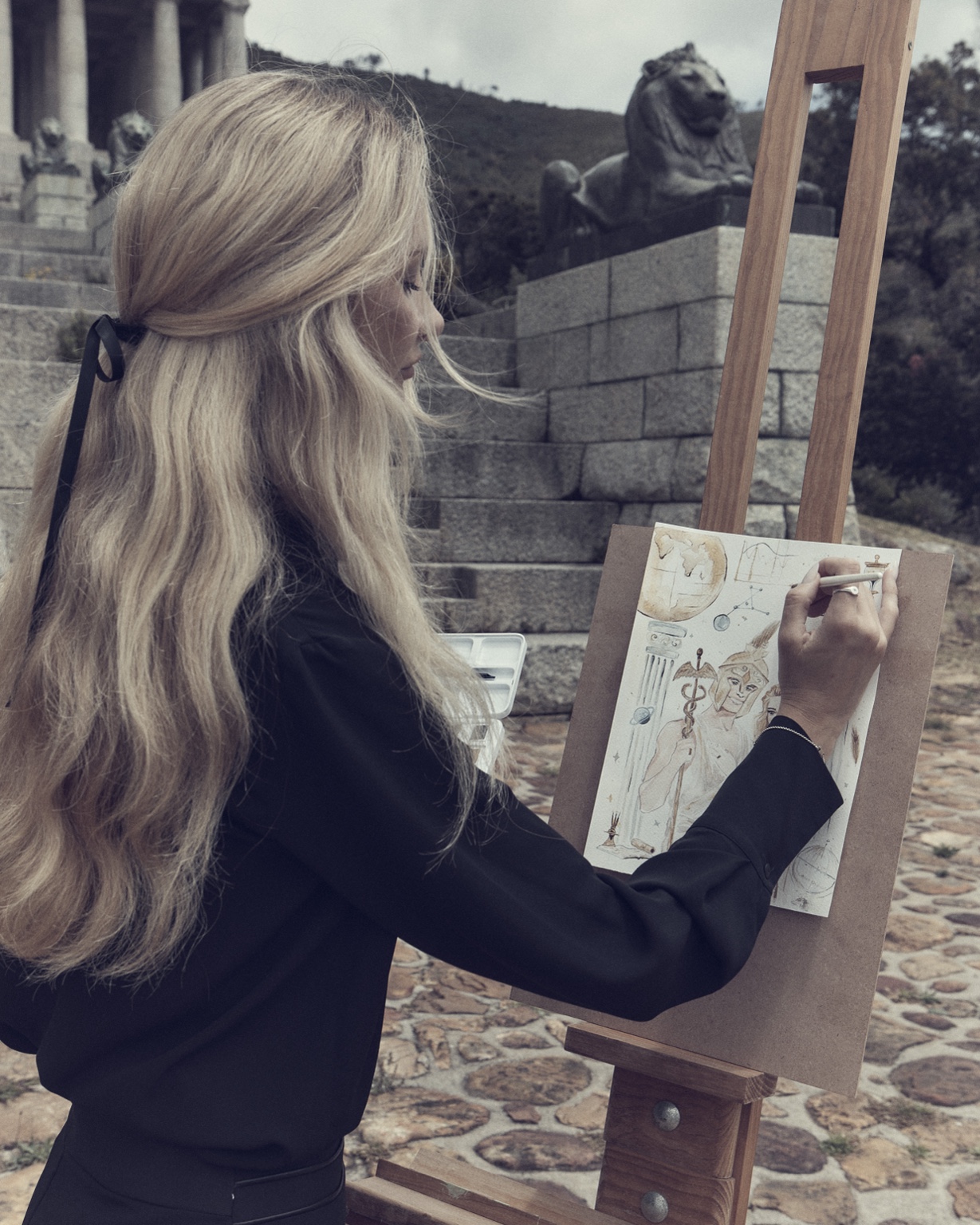 Nataliia drawing at her easel in a black outfit